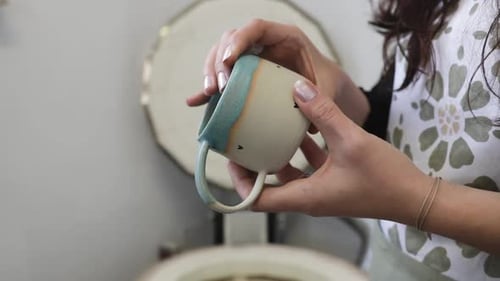 Woman Examining Handmade Ceramic Mug in Workshop