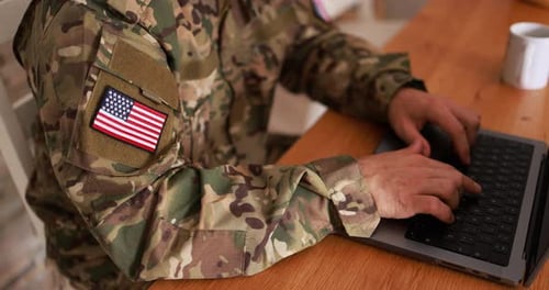 American soldier man in military uniform working with computer laptop at home