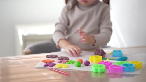 Child Plays with Plasticine on Table