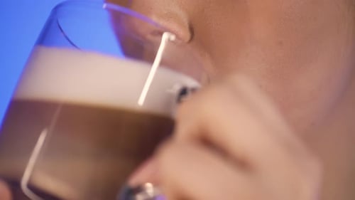 Primer plano extremo de una mujer bonita mientras disfruta de un café con leche y capuchino recién hecho