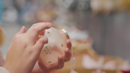 Girl Inspecting Christmas Ornament in Holiday Shop