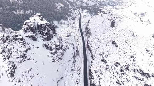 Aerial View of Vehicles Driving on a Snow Covered Mountain Road