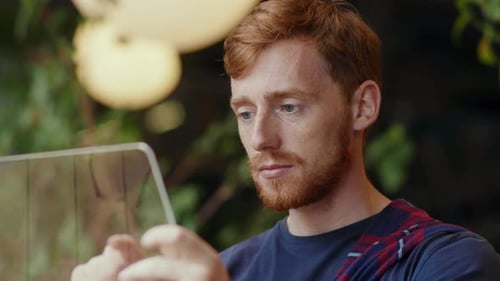 Junger konzentrierter Geschäftsmann nutzt innovativen Tablet-Computer beim Surfen in sozialen Netzwerken im Internet