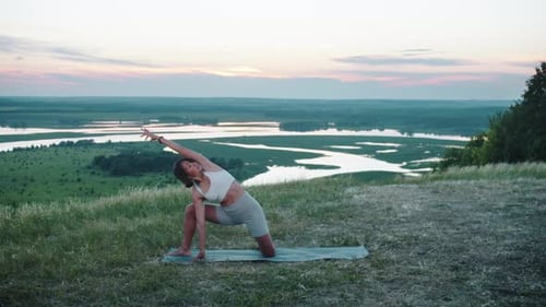 Yoga sur la colline Une femme faisant de l'exercice sur un tapis de yoga au coucher du soleil