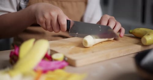 Asiatische Frau schneidet zu Hause Bananen auf dem Tisch