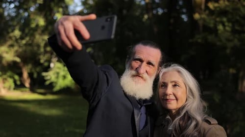 Old Grayhaired Grandfather and Grandmother Take a Selfie in the Park