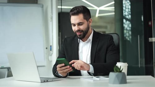 Young Adult Celebrates Success in Office Using Phone
