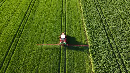 Tractor Spreading Artificial Fertilizers in Green Field Farming Tractor Spraying on Field with