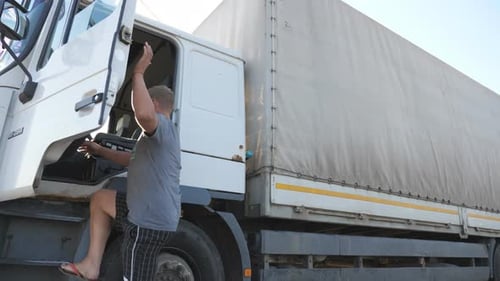 Man Climbing Into White Semi Truck in Daytime
