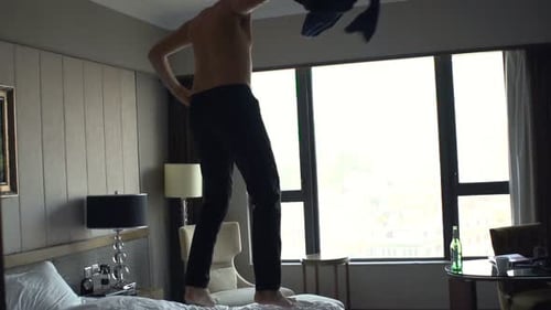 Man Takes Off Clothes and Jumps on Bed