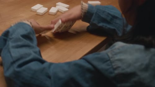 Criança anônima olhando para seus azulejos enquanto joga dominó