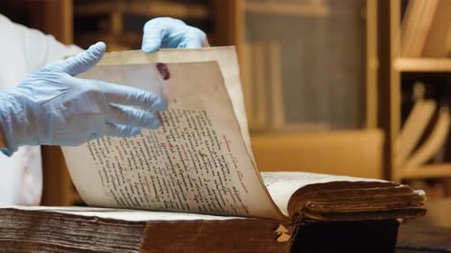 Gloved Hands Turn Pages of Old Manuscript