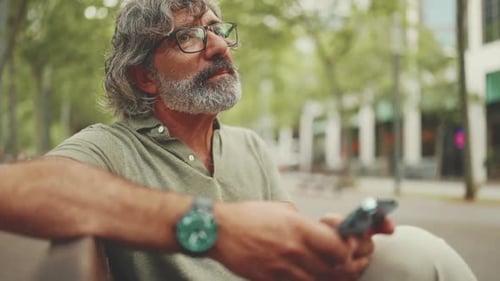 Man With Gray Hair Using Phone in Park