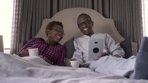 Senior Couple Relaxing in Bed with Tablet