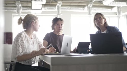Three Women Collaborating Around a Table With Laptops