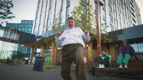 Young And Stylish Male Hip Hop Dancer Is Freestyling On City Street Among Modern Buildings In the