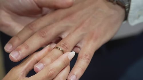 Woman Puts Gold Ring on Man's Finger