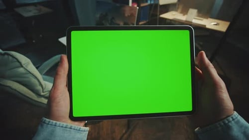 Man Holding Scrolling a Tablet Computer with a Horizontal Green Screen in the Office Mockup Display