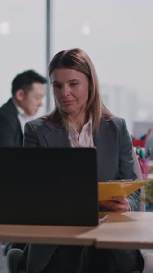 A Professional Woman in a Smart Suit Works Focused at Her Desk