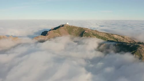Clouds surrounding mountain with weather station on top in Madeira, aerial