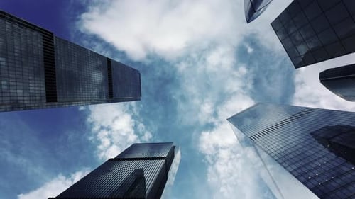 View From Below of Tall Modern Glass Skyscrapers Against a Cloudy Blue Sky These Buildings House