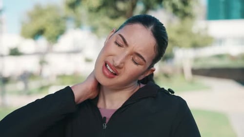 Woman Rubbing Neck in the Park