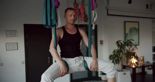 Man Doing Aerial Yoga Inside Bright Room