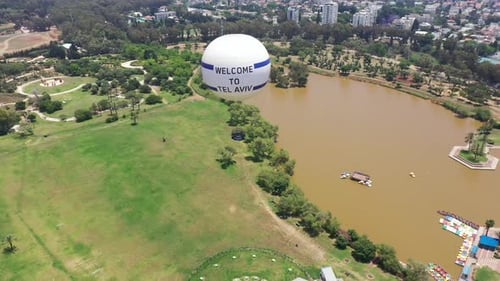 Aerial Shot Of Hot Air Balloon Descending Over Yarkon Park Against Sky In City
