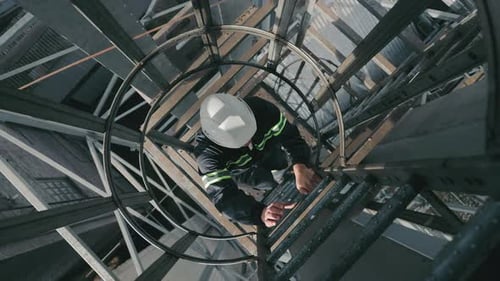 Industrial Worker Climbing Ladders Up Top View Worker with Hard Hat Ascending the Ladder in an