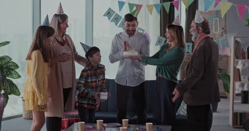 Family celebrating birthday with cake and party hats