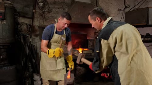 Blacksmiths Forging Red Hot Metal in Workshop