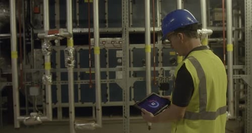 Männlicher Ingenieur inspiziert einen industriellen Anlagenraum mit einem digitalen Tablet