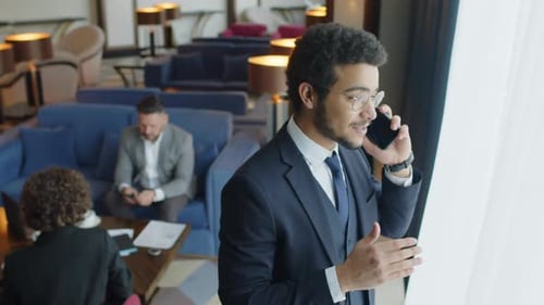 Businessman Talking on Phone while Spending Time in Business Lounge of Hotel