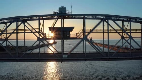 Vista aérea de los rayos del sol a través de la estructura metálica del puente elevador sobre el puerto: toma de rastreo de Zumbidos La