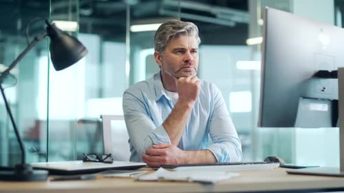 Exhausted, overworked mature office worker sitting in the workplace with a severe headache massaging