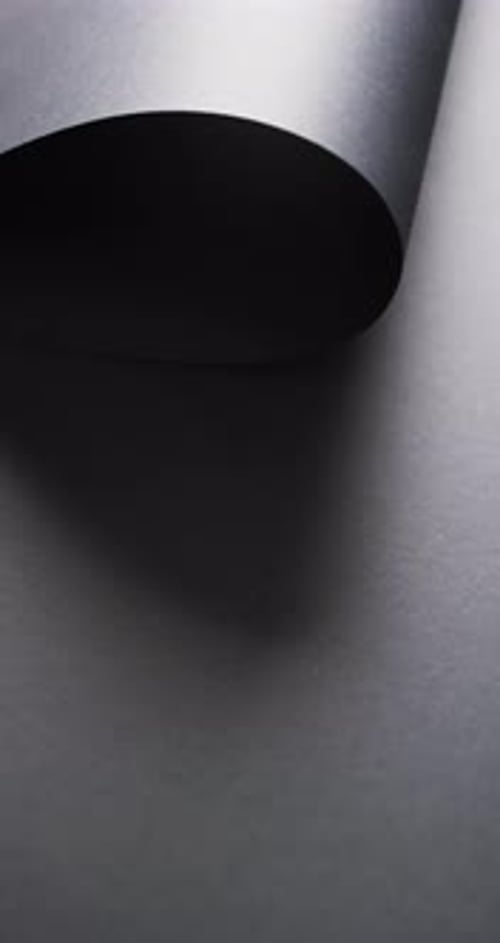 Vertikales Video der Nahaufnahme einer schwarzen Papierrolle und des Kopierraums auf schwarzem Hintergrund