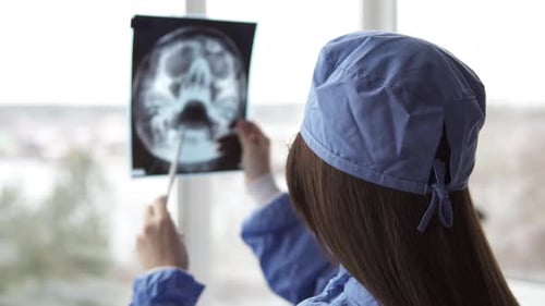 A doctor in a hospital room is examining an x-ray of the aftermath of an injury.