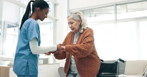 Young Adult Assists Senior Woman into Wheelchair