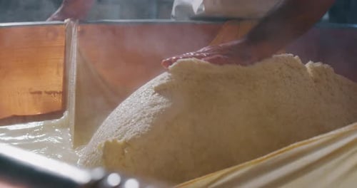 Gros plan au ralenti d'un fromager prépare une forme de parmesan à base de fromage frais et biologique