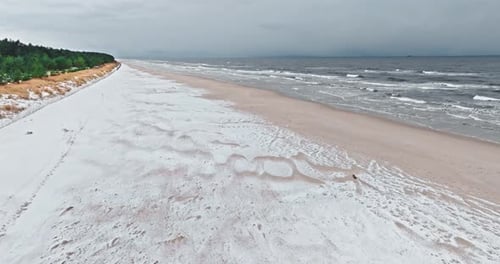 Aerial view of snowy winter beach by Baltic sea.