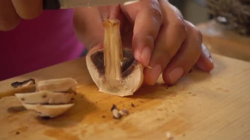 Mushroom Being Sliced on Cutting Board
