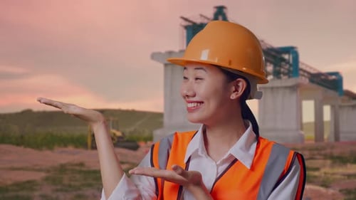 Close Up Of Asian Female Engineer Smiling And Pointing To Side at Construction Site