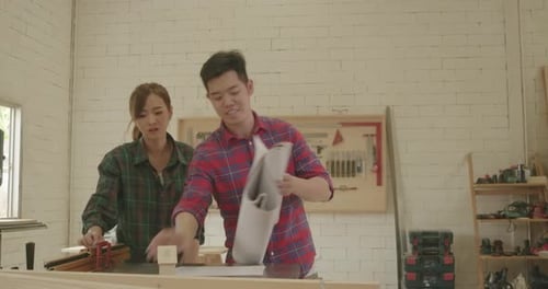 Two carpenter teamwork male and female reading blueprint building design project to customer