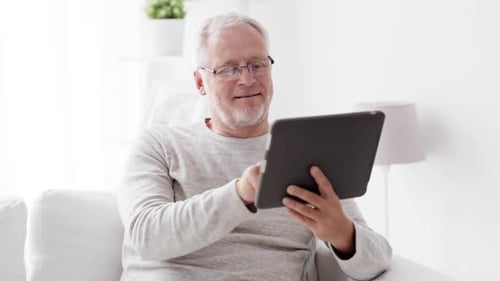 Senior man relaxes on sofa using tablet device
