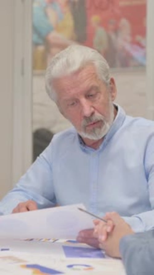 Senior Man Reviewing Documents in Meeting Indoors