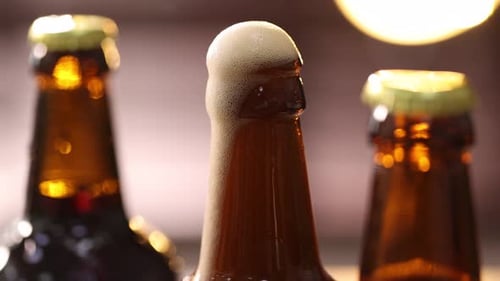 Close up of brown beer bottles with foam