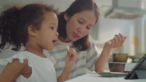 Girl Using Tablet with Mother Watching in Kitchen