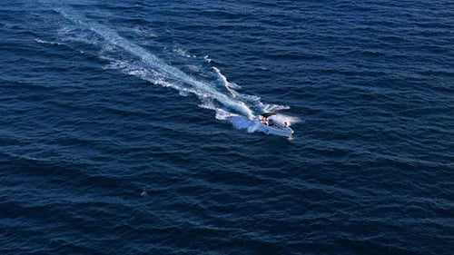 Fishing boat leaves large wake white wash as it drives across open ocean