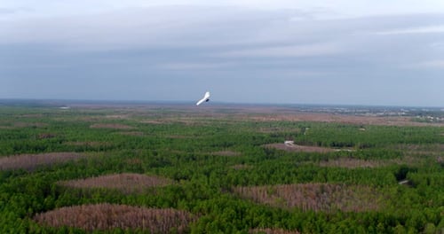 Hang Glider Flying in Sky Above Forest and Fields, Aerial Drone Aerial