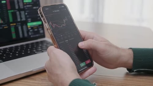 Bitcoin Candle Graphs on the Phone Screen Man Trader Hands Close Up Holding Smartphone Trading App